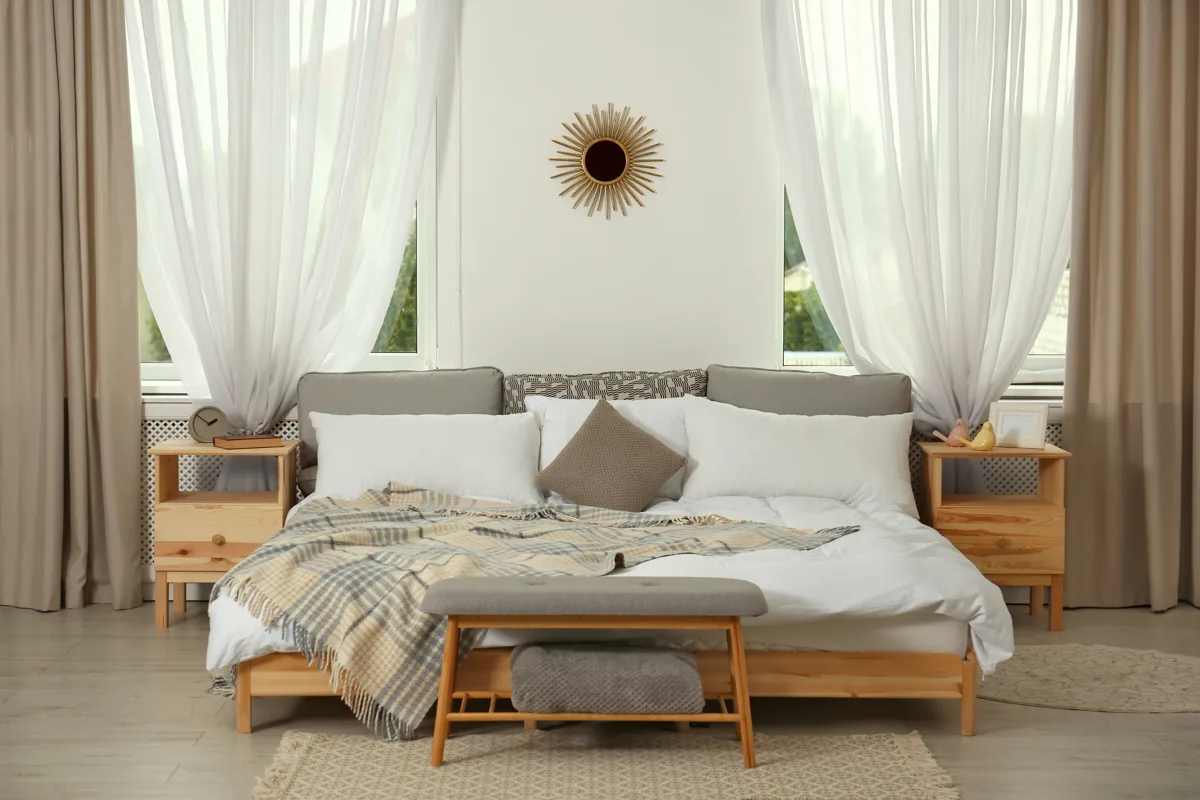 Neutral bedding and cushions in a light-filled bedroom