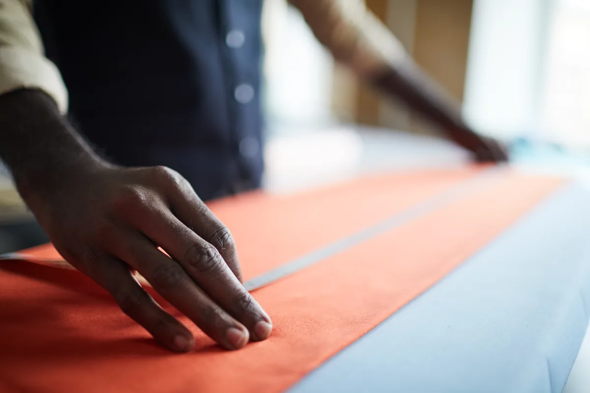 A craftsperson preparing fabric at a cutting table