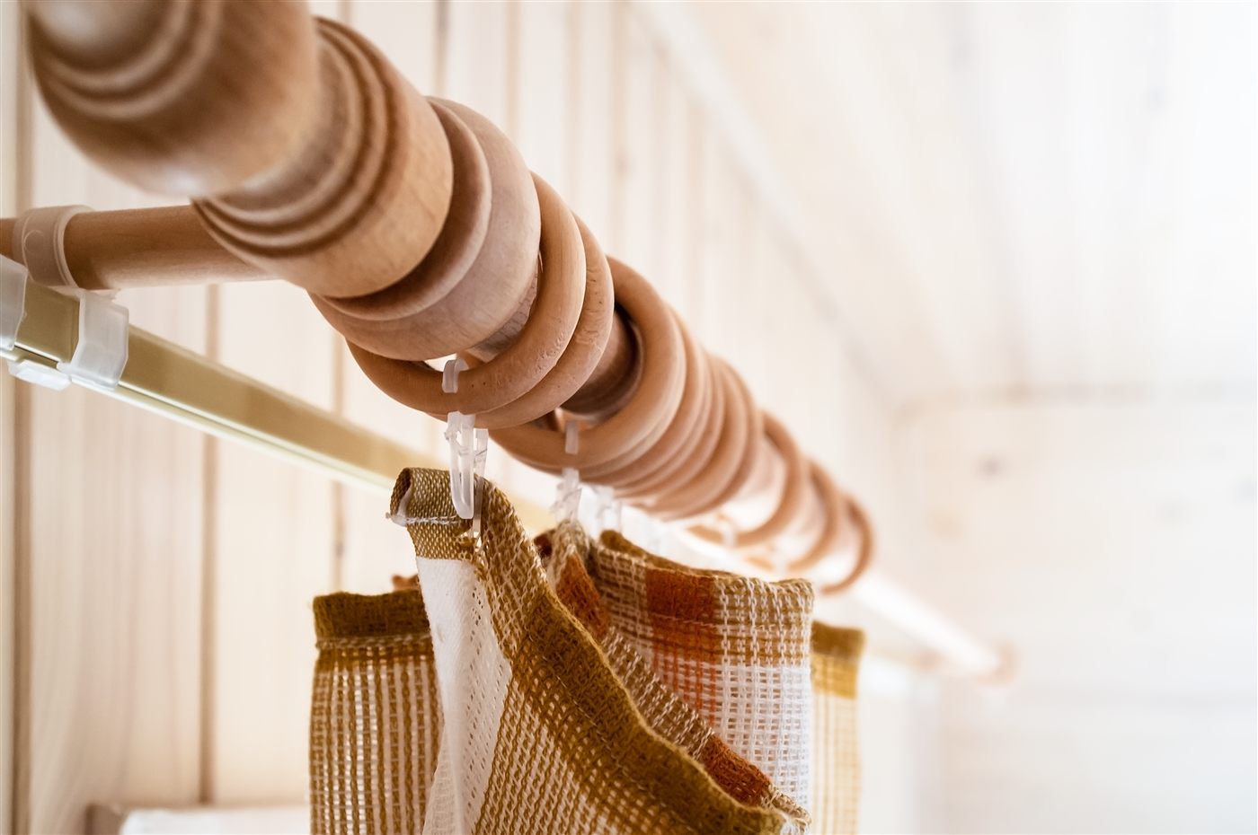 Close view of a wooden curtain rod, rings and textured fabric curtains