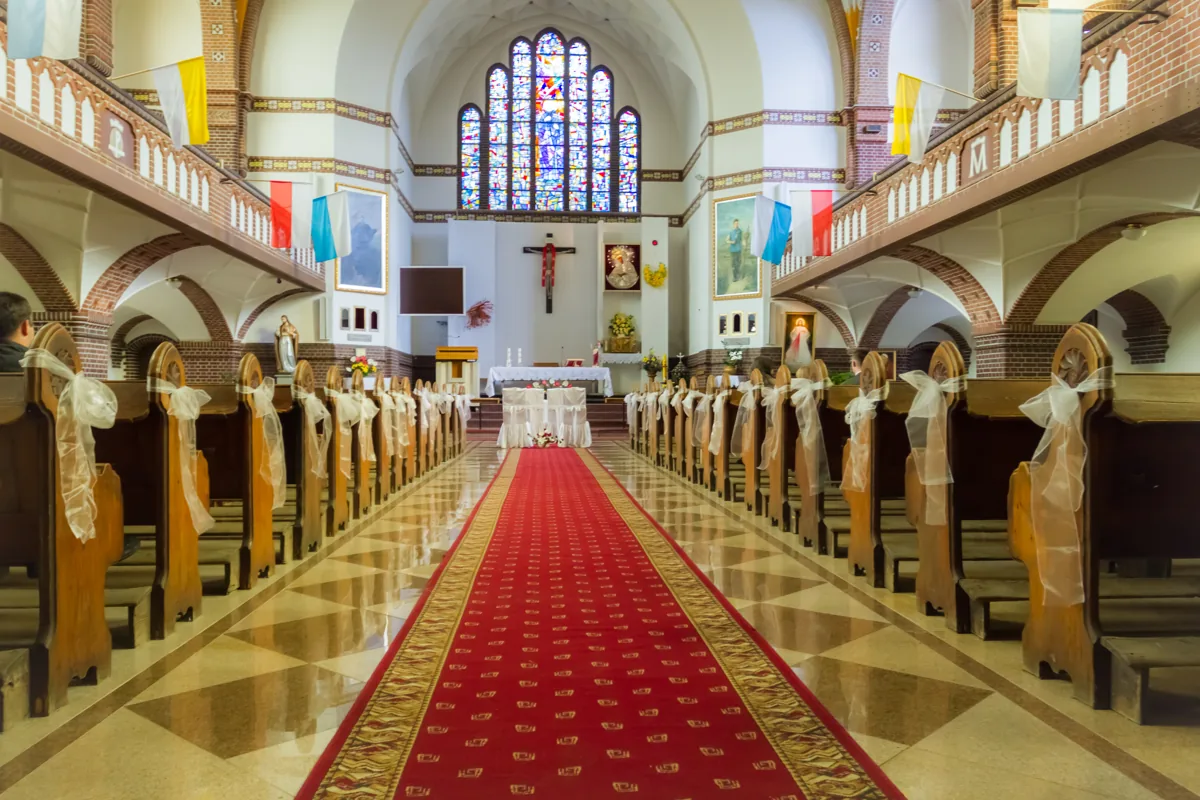A church aisle dressed with flowers and white wedding linens