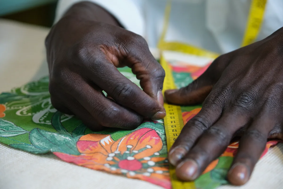 Hands measuring fabric with a tape measure