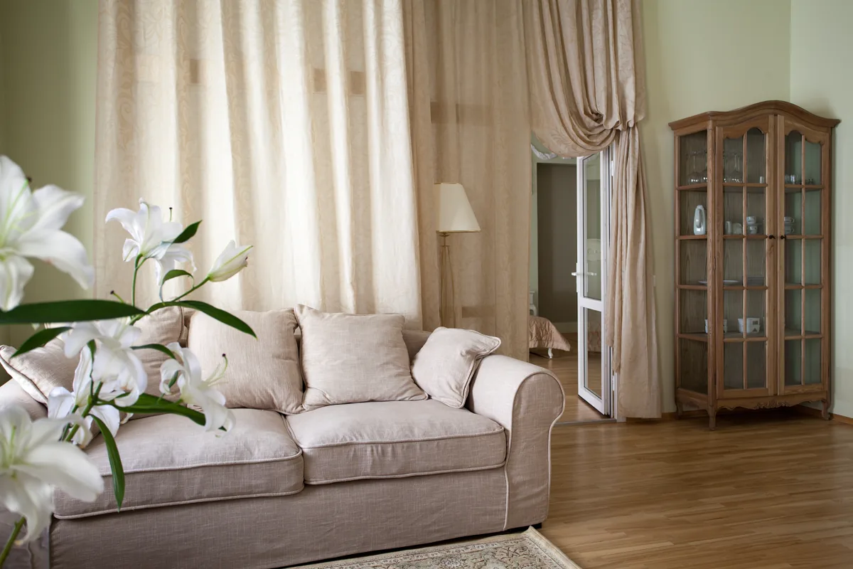 A cream sofa and flowing curtains in a warm interior