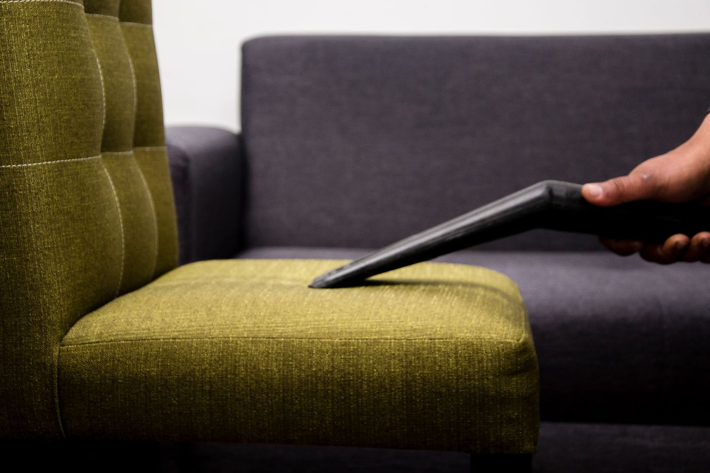 A chair's fabric seat being carefully cleaned with a vacuum attachment